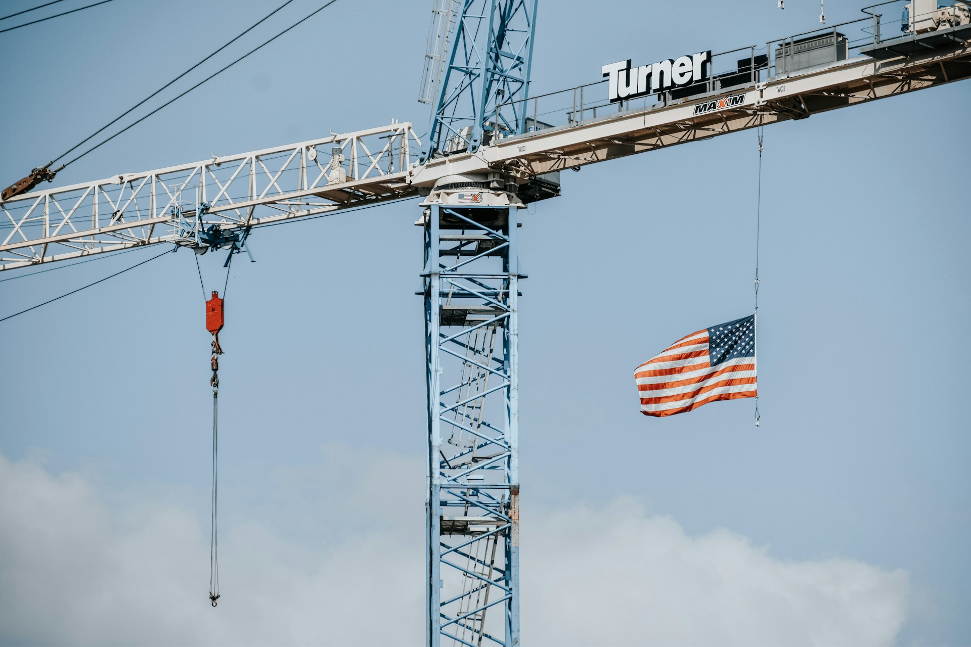an American flag hanging from a crane on a construction site